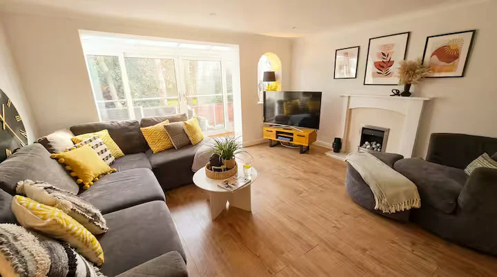 Bright lounge with grey corner sofa, mustard accents and fireplace