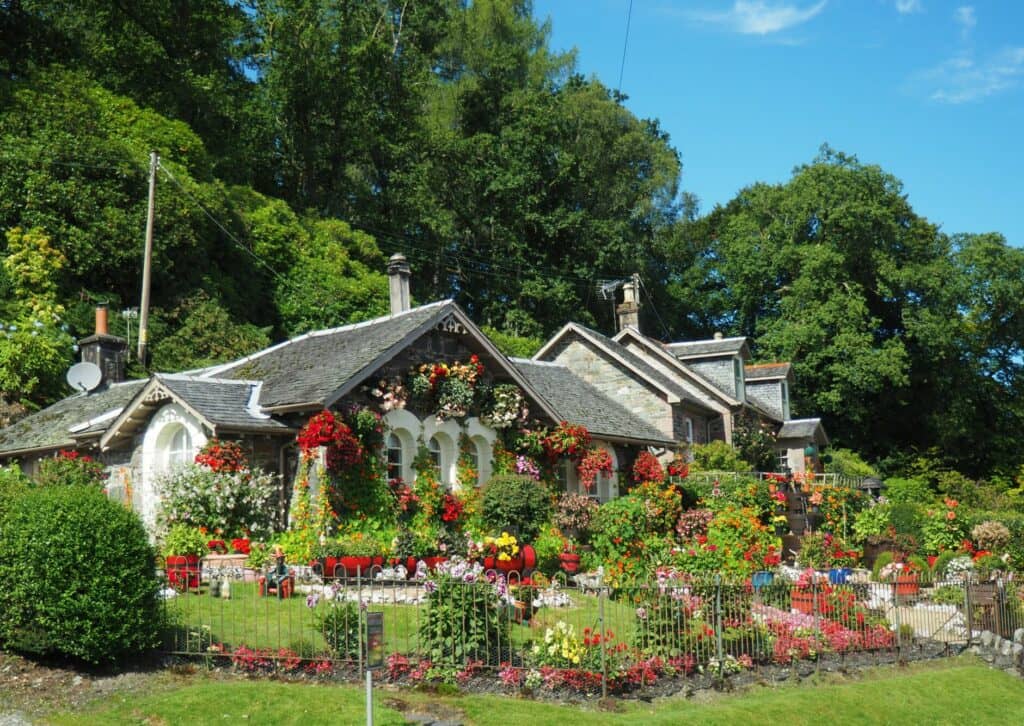 Beautiful British stone cottage covered in colourful summer flowers — the kind of property managed by Full Bed Hosts